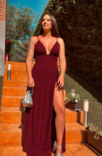 Vestido largo de fiesta Yaizacolor vino tinto con escote pronunciado en V y abertura lateral en la pierna. Vista frontal de modelo con vestido de tirantes para invitada de boda o evento. SXìA 